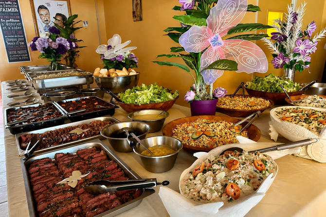 Buffet avec plats variés, salades et centres de table floraux dans une salle à manger décorée
