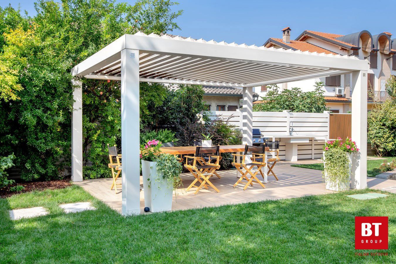 Un pergolato bianco con un tavolo e delle sedie sotto in un cortile.