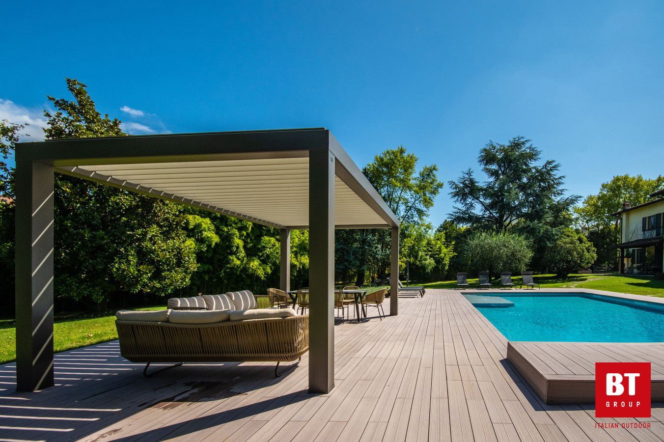 Un patio con pergolato e piscina sullo sfondo.