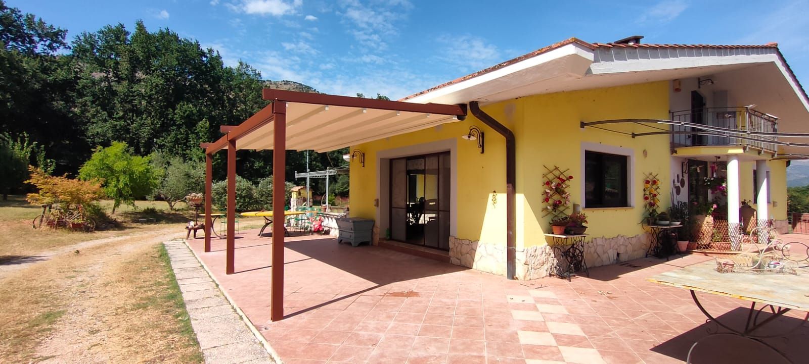 Una casa gialla con un pergolato davanti