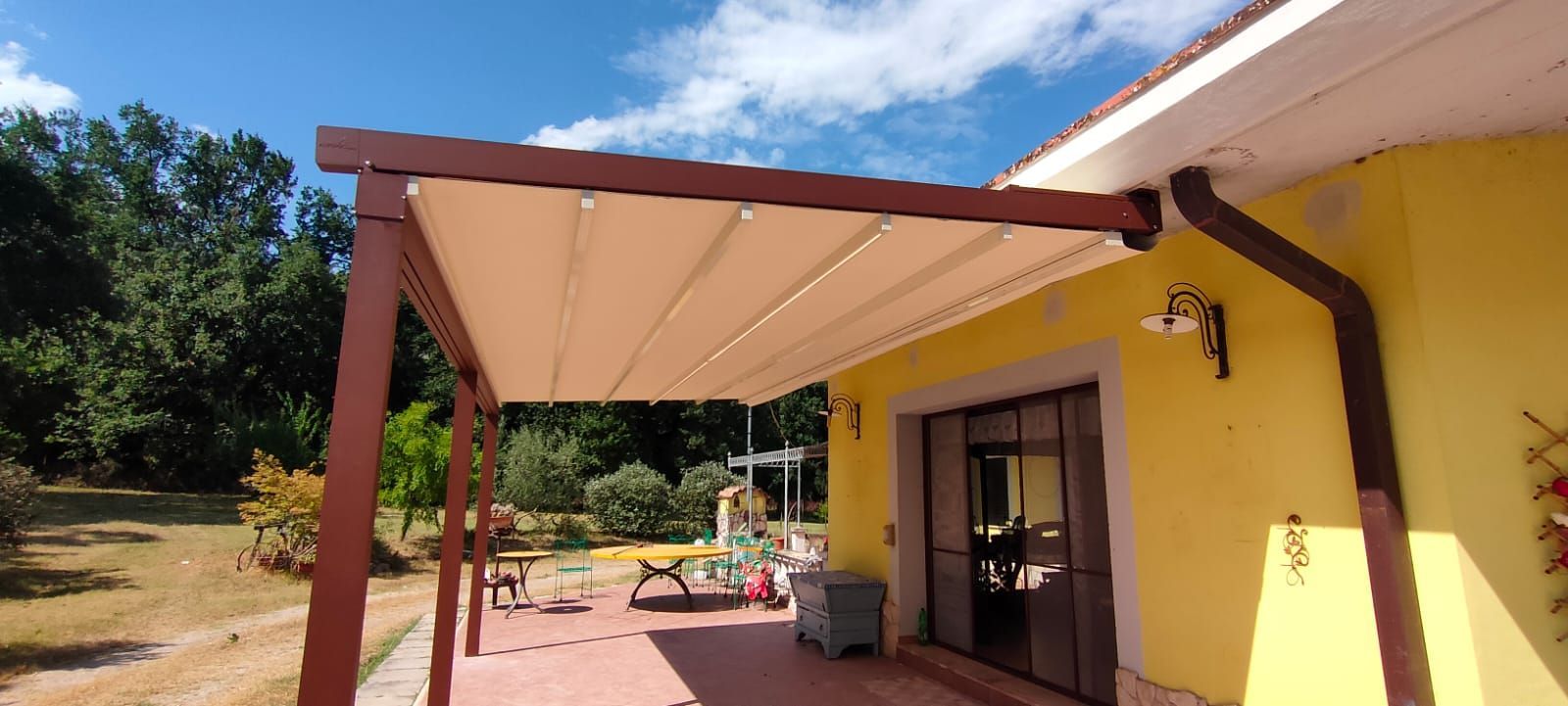 Una casa gialla con un pergolato sul lato