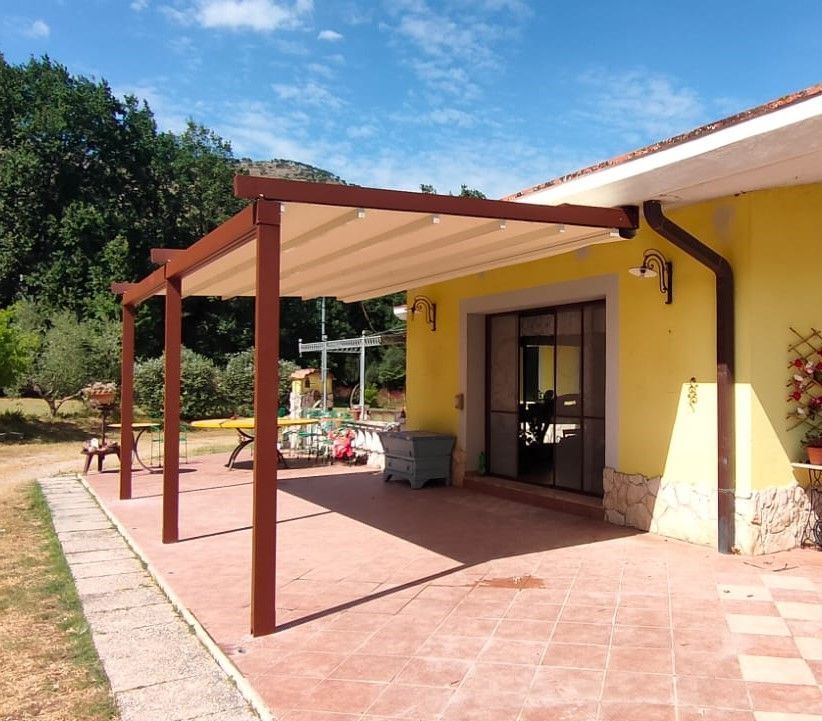Una casa gialla con un pergolato sul lato