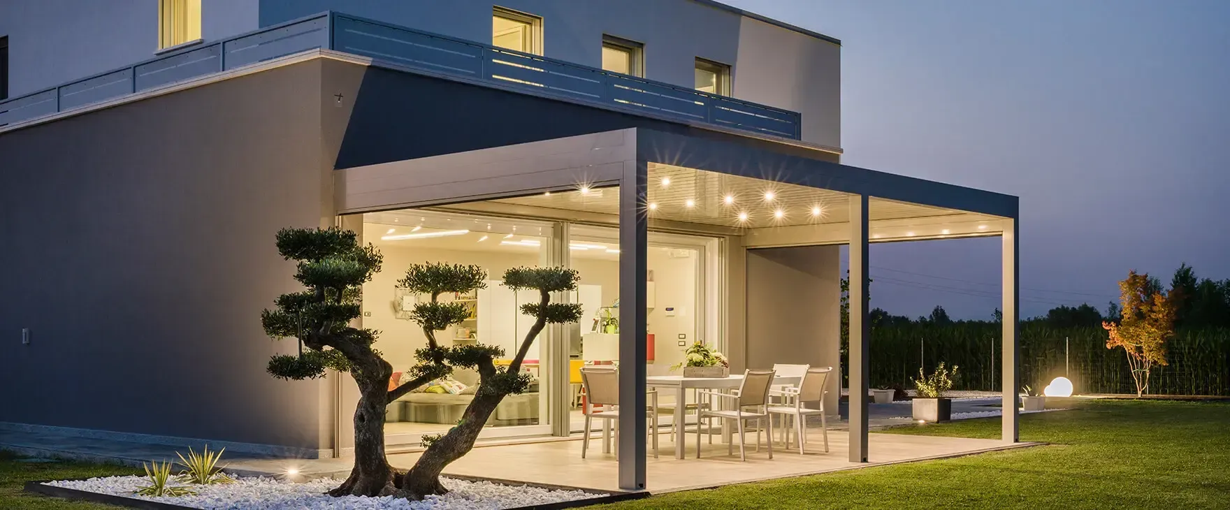 Una casa con un pergolato e un albero davanti di notte.