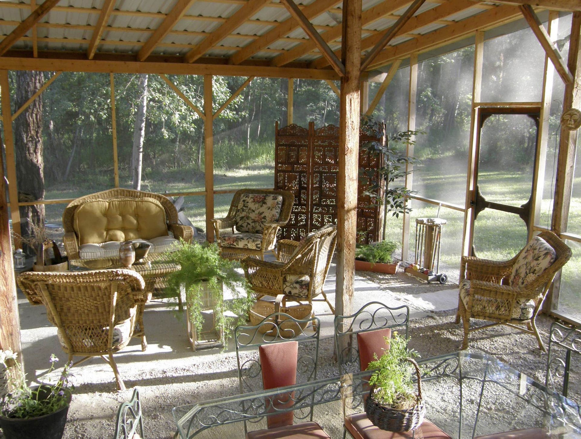 A screened in porch with wicker furniture and a table