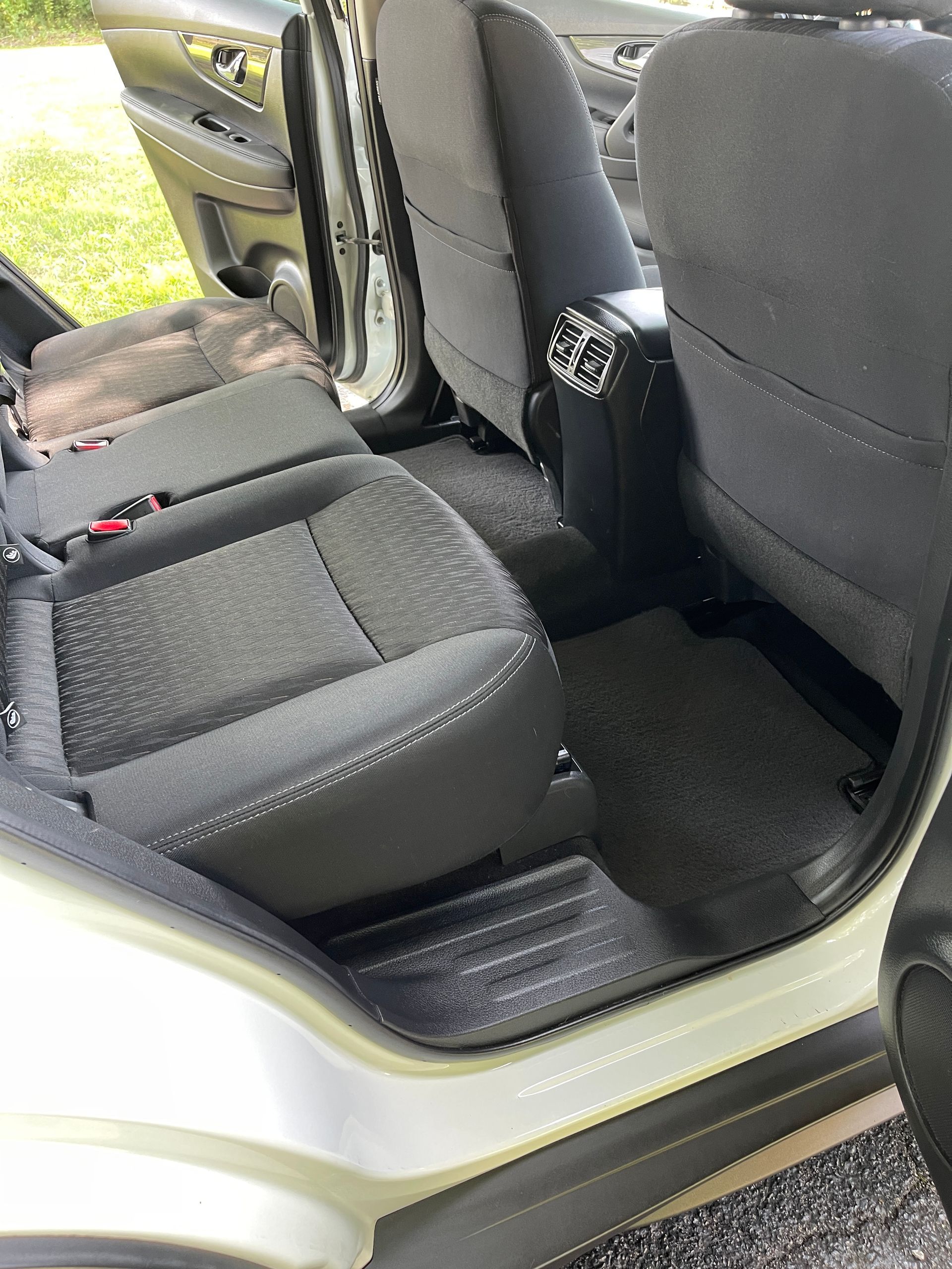 The inside of a car with the door open and the seats folded down.