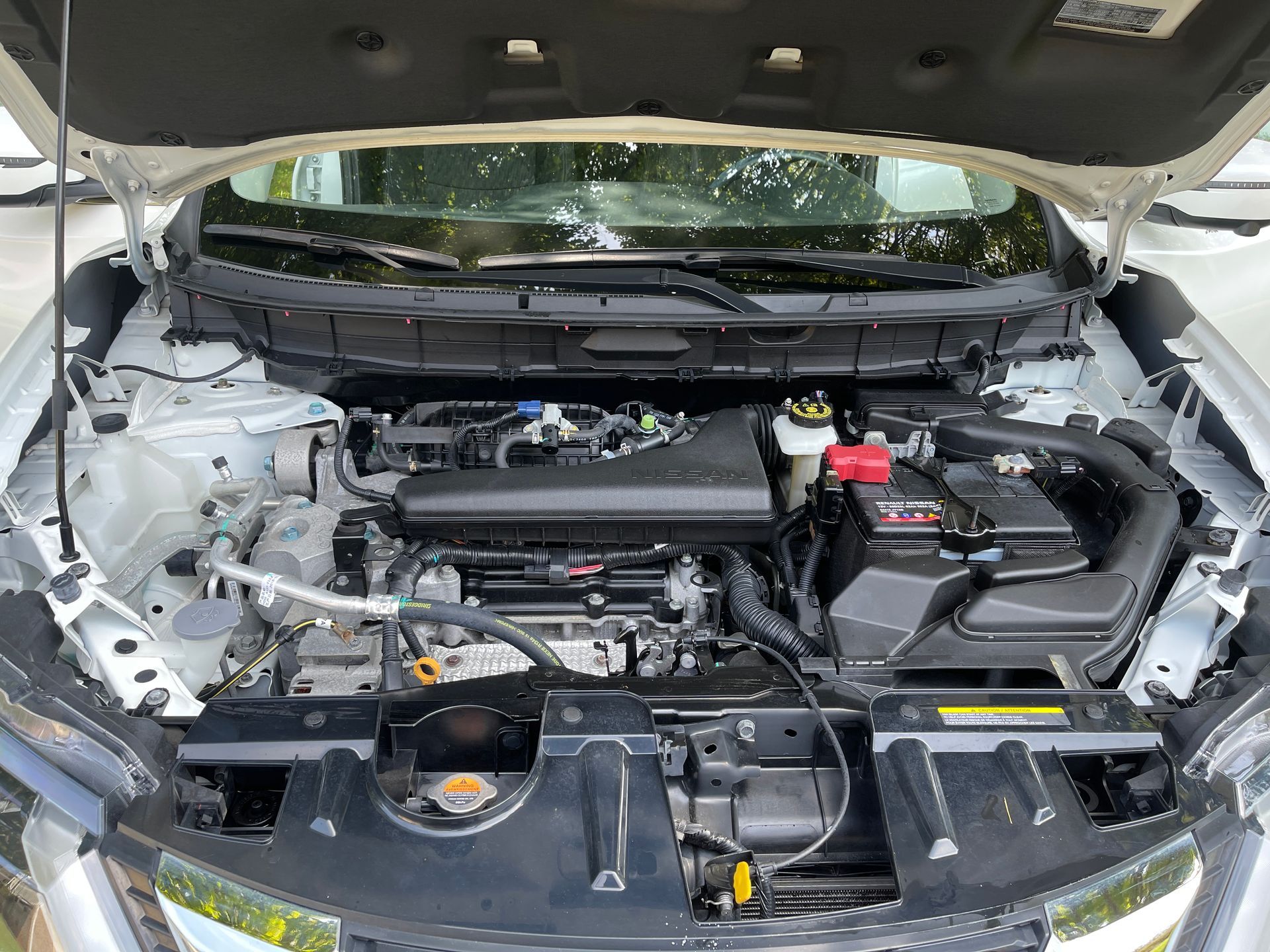 The engine of a nissan rogue is shown with the hood open.