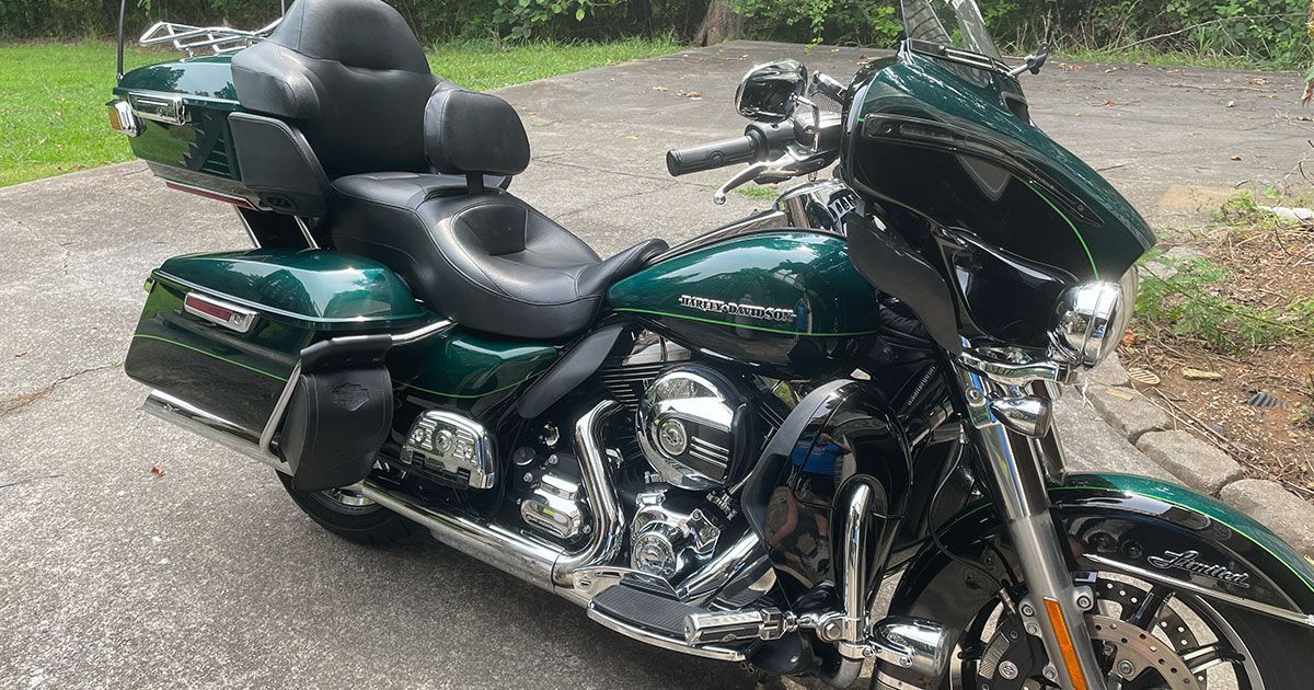 A green harley davidson motorcycle is parked on the side of the road.
