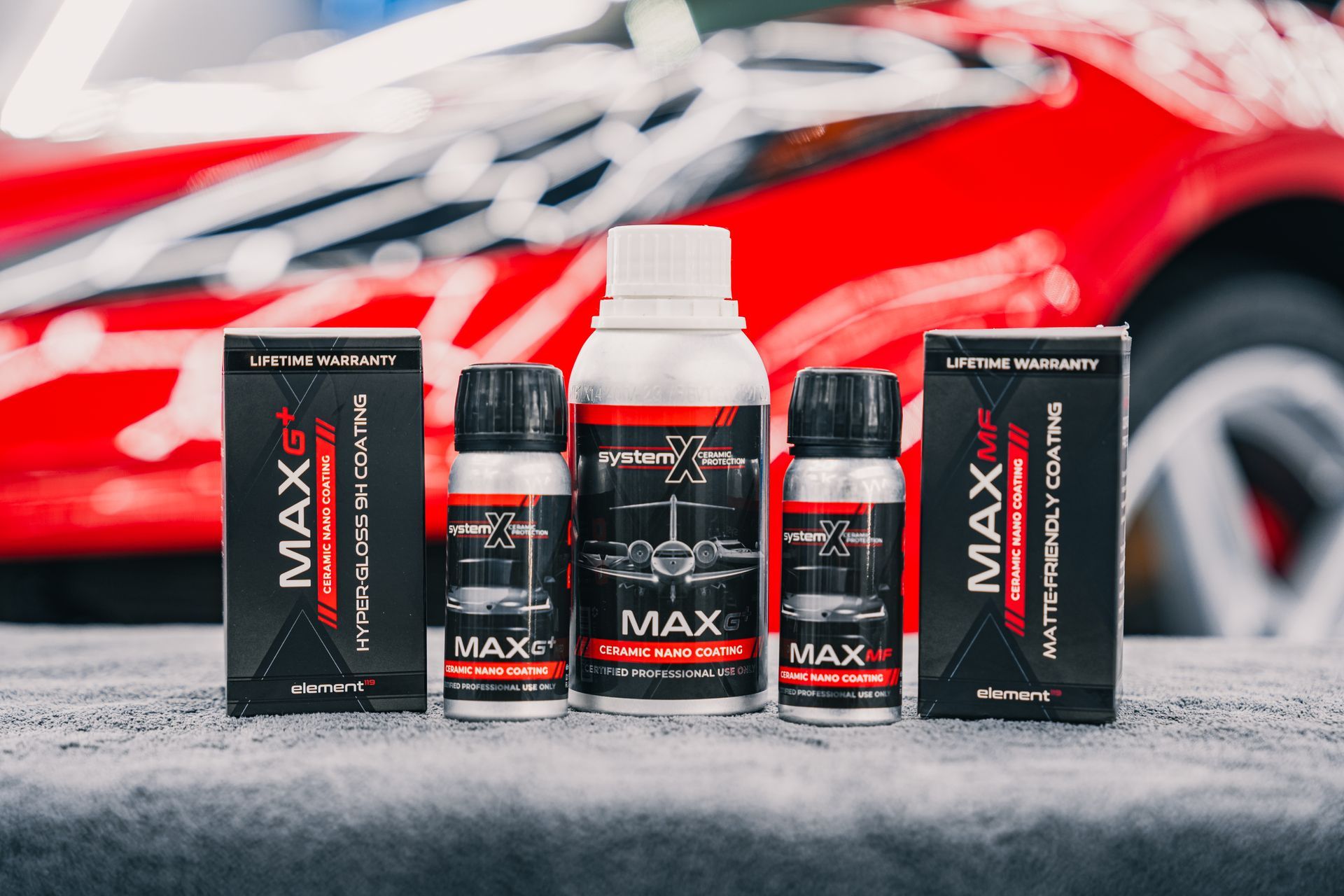 A set of car detailing products, including bottles and boxes, with a red car blurred in the background.