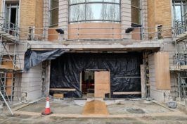 A building under construction with scaffolding and a cone in front of it.