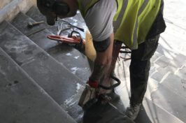 A man is cutting concrete stairs with a chainsaw.