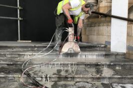 A man is cutting concrete steps with a saw.