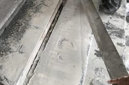 A person is cutting a piece of metal with a saw.