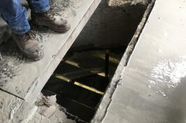 A person is standing in a hole in the ground next to a staircase.
