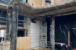 A building is being demolished and a ladder is in the foreground.
