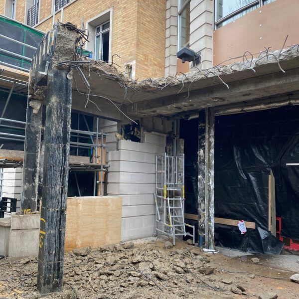 A concrete structure is being demolished in front of a building