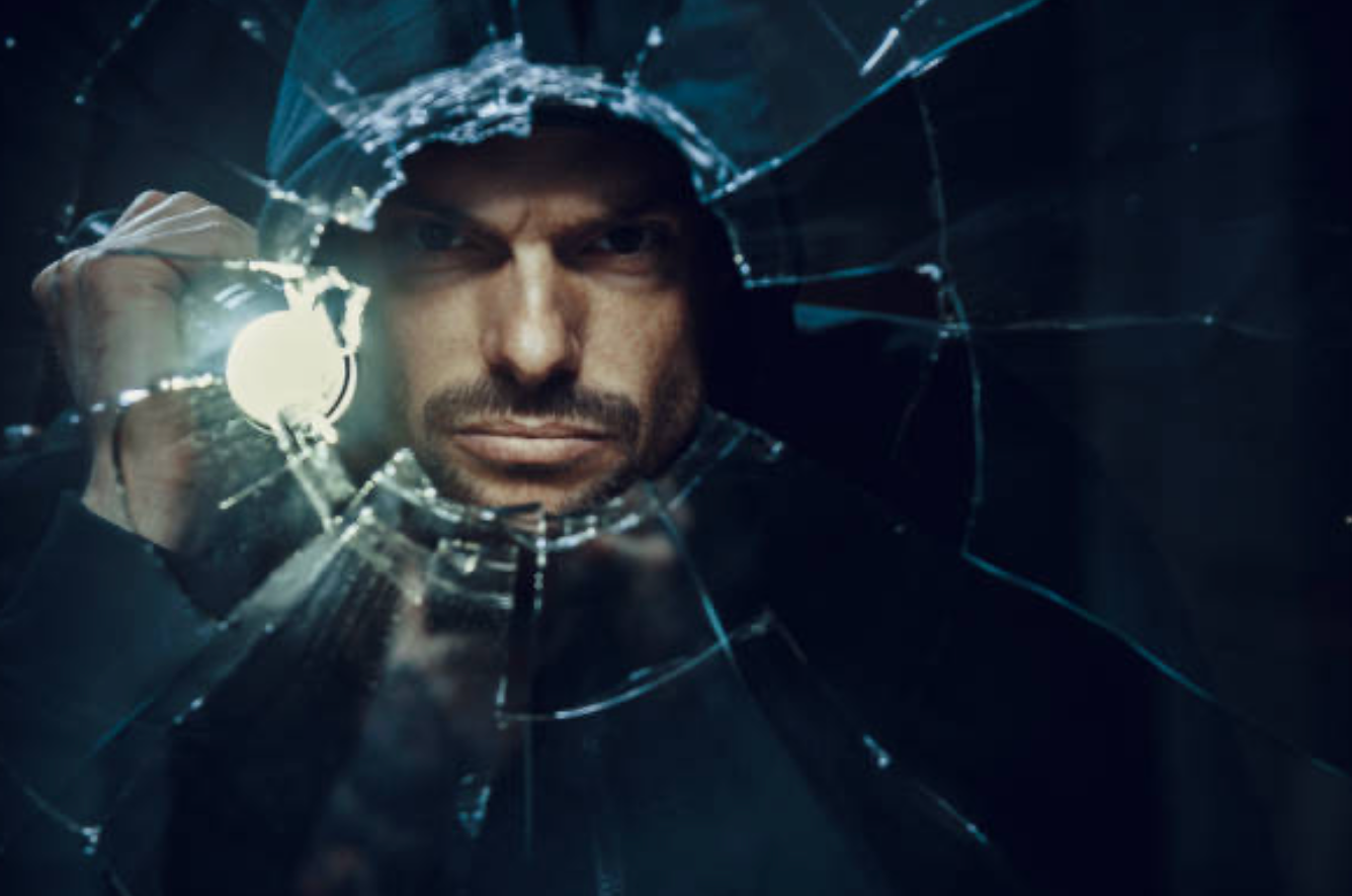 a photo of a man looking through a broken glass