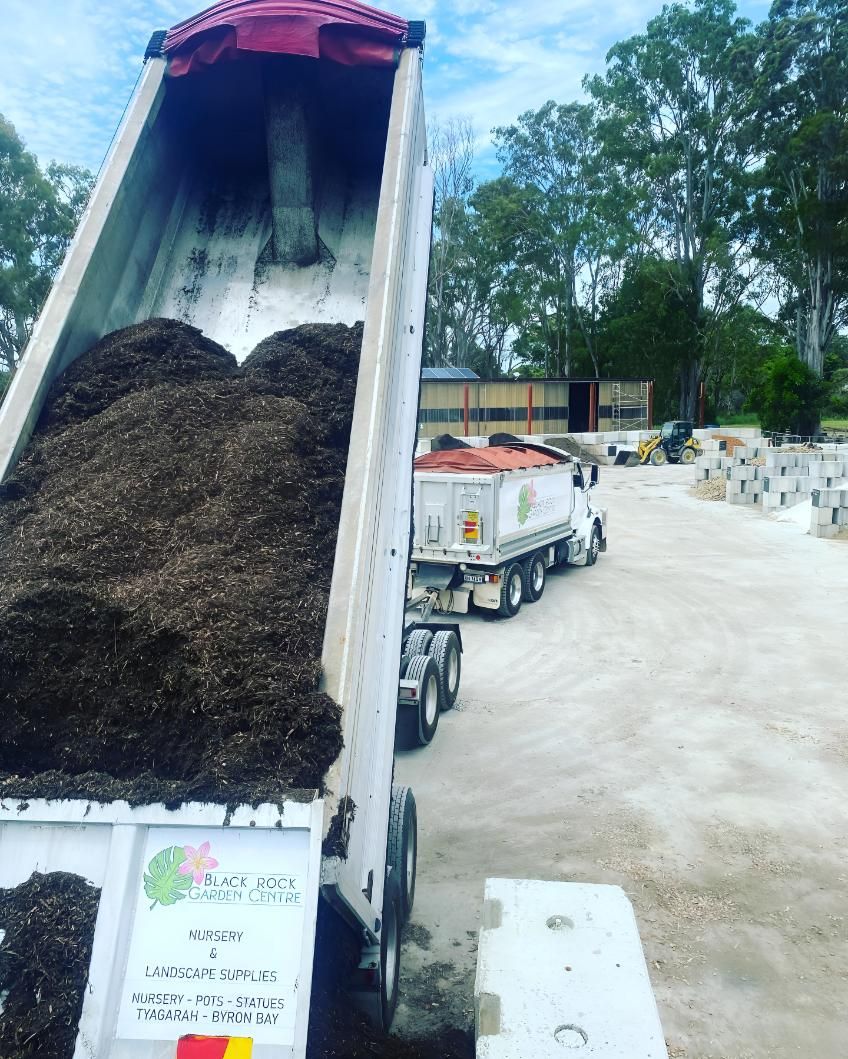 A Dump Truck is Being Loaded With Dirt in a Parking Lot — Black Rock Garden Centre In Tyagarah, NSW