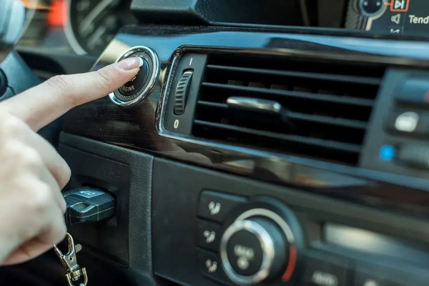 A person is pressing a button on the dashboard of a car.