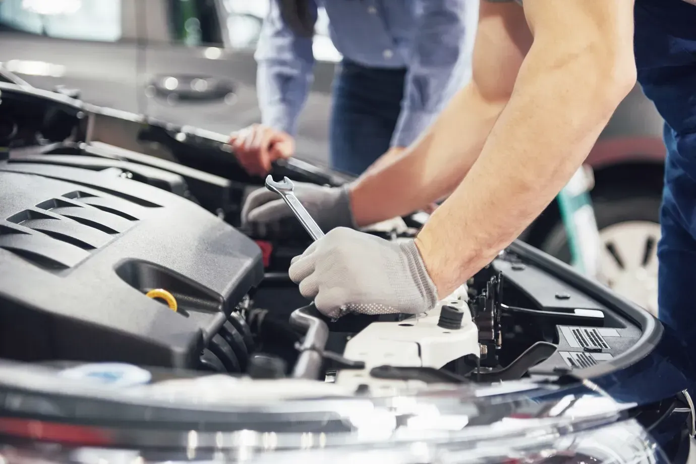 Two men are working on the engine of a car.