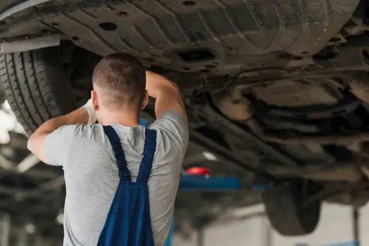 A man is working under a car in a garage.