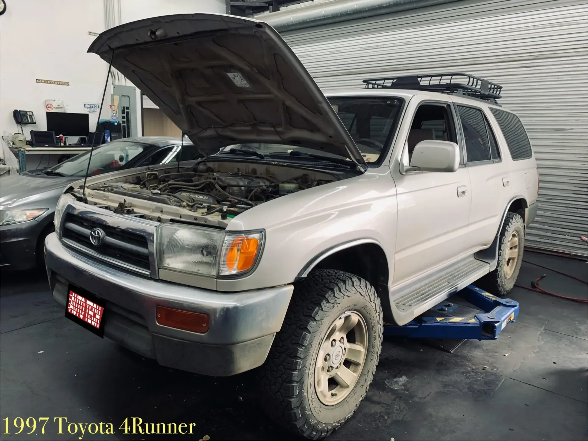 A man is working on the engine of a car with the hood open.