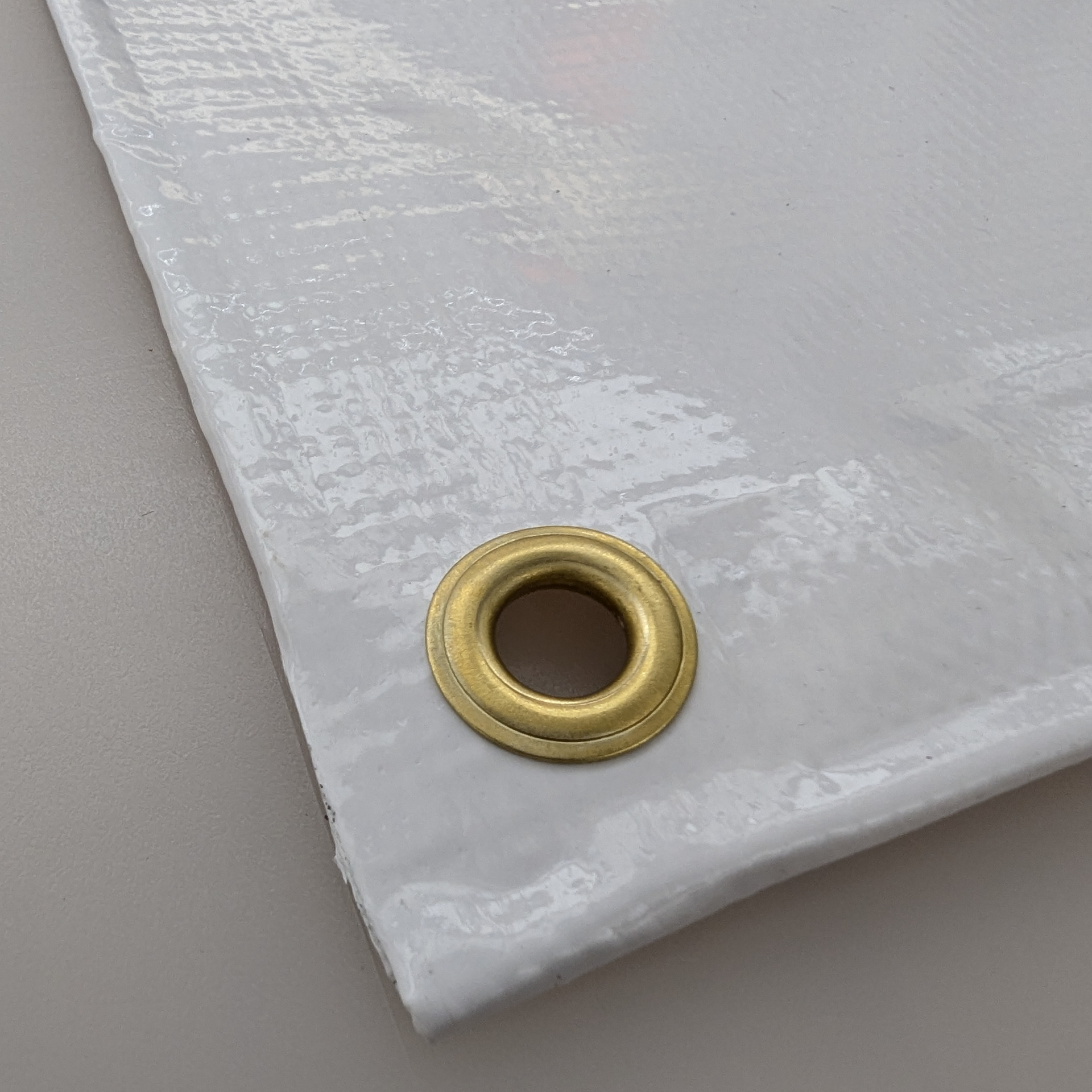 A close up of a white tarp with a brass eyelet on it by Press Enterprise Commercial Printing