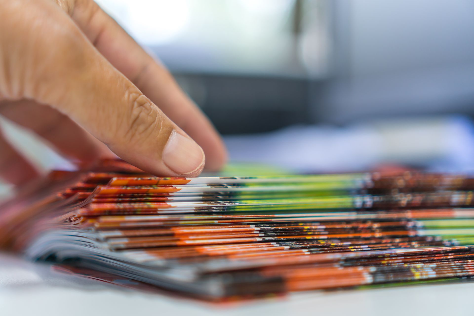 Hand reaches for a stack of colorful brochures, freshly printed. Hand reaches for a stack of colorful brochures, freshly printed.