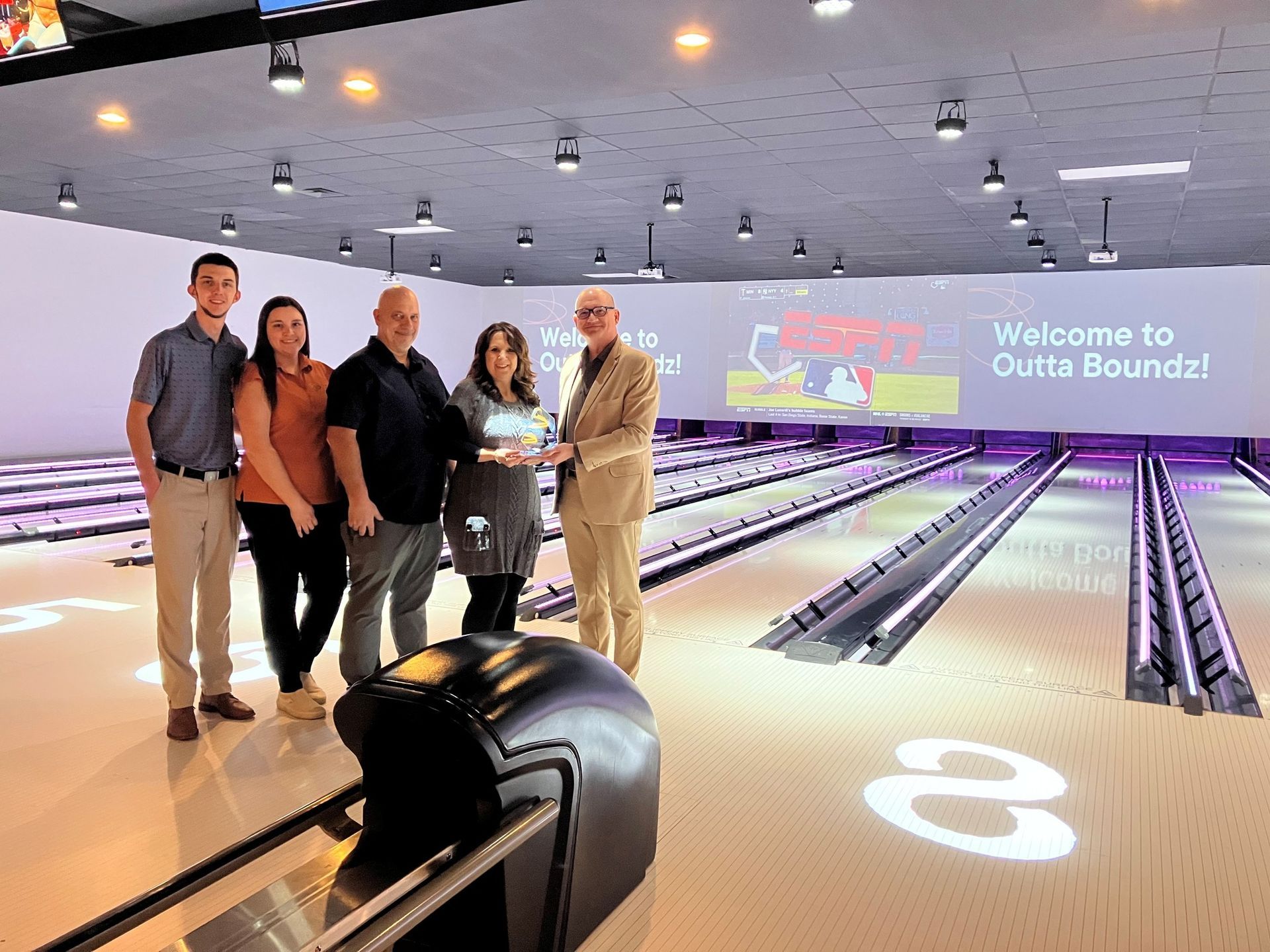 People with an award near bowling lanes.