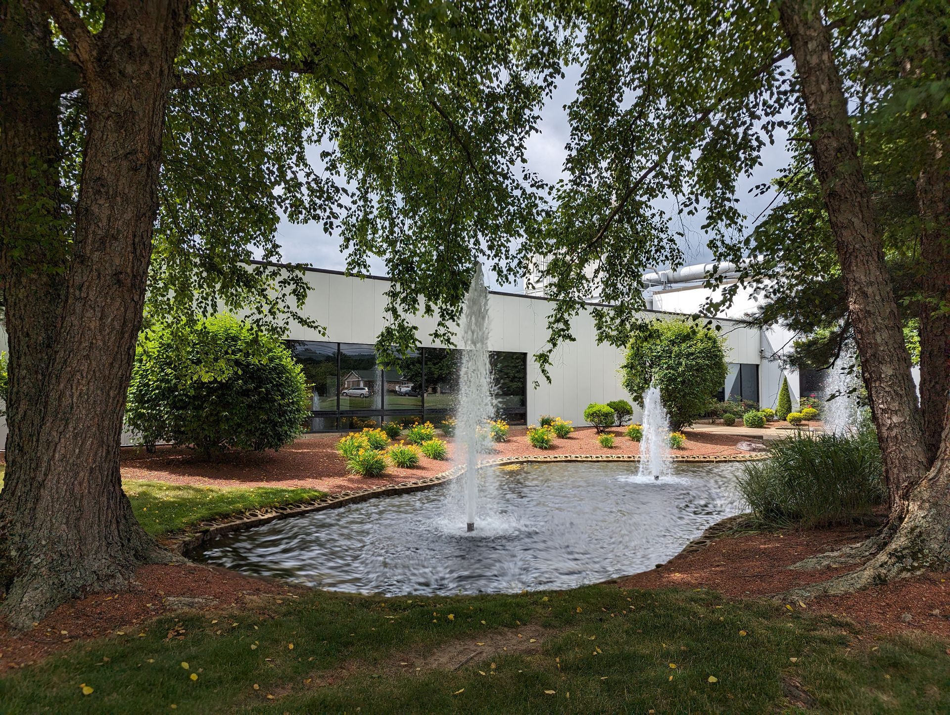 There is a fountain in the middle of the park in front of the press enterprise commercial printing building.