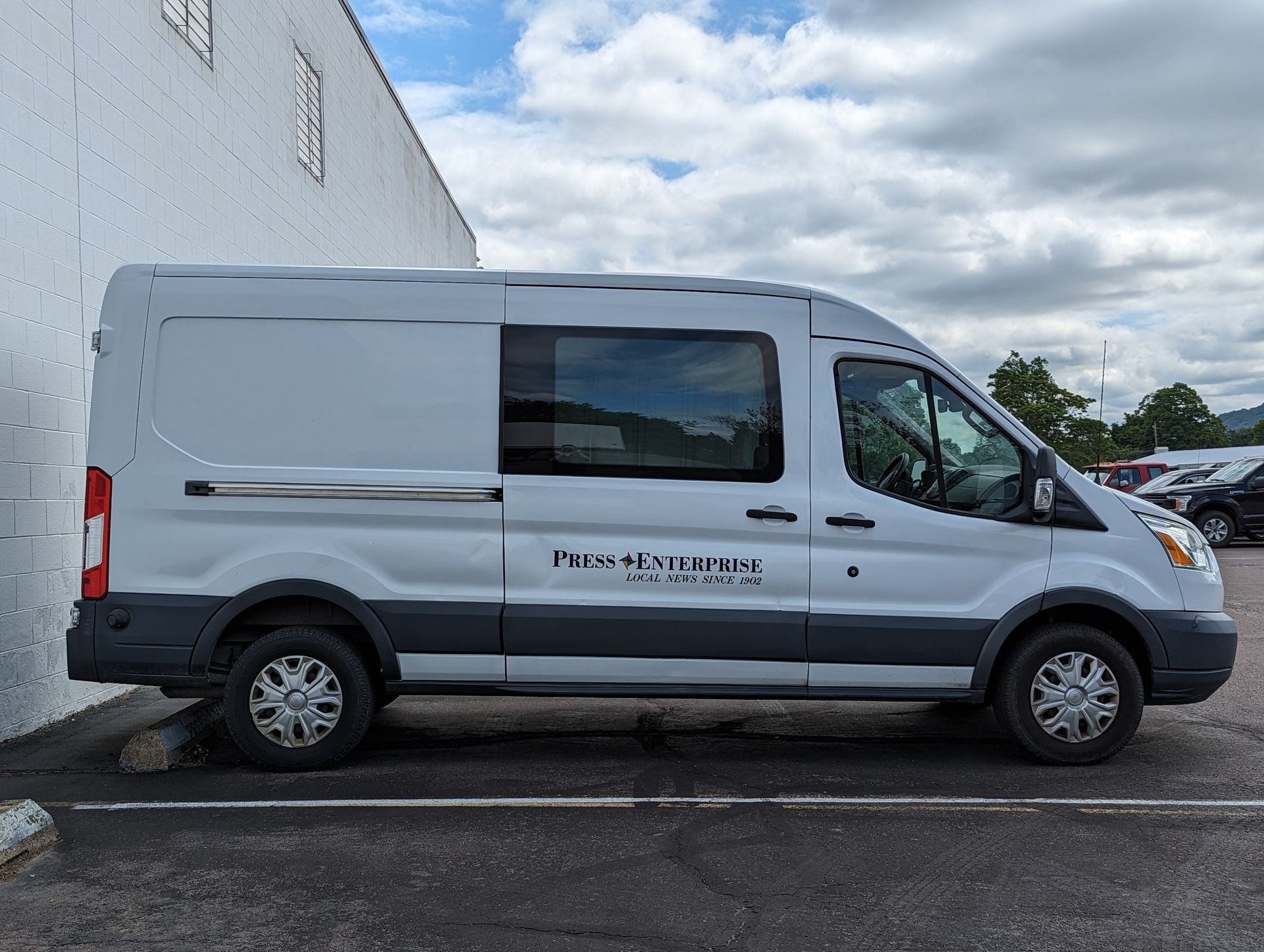 A white van is parked in front of a white building Press Enterprise Commercial Printing Icon