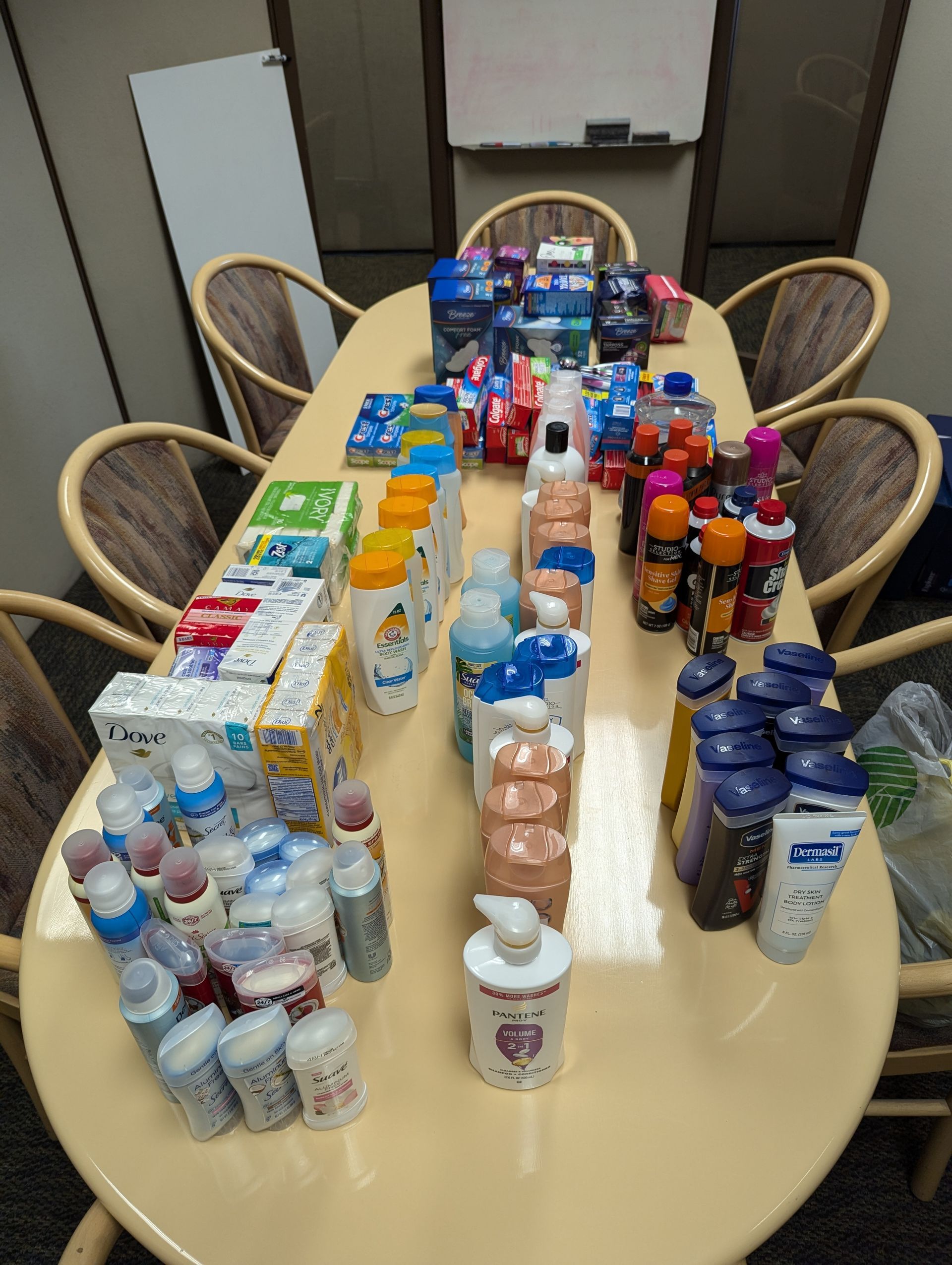 Assortment of personal care items on an oval table, including bottles of shampoo, lotion, and boxes of medications.