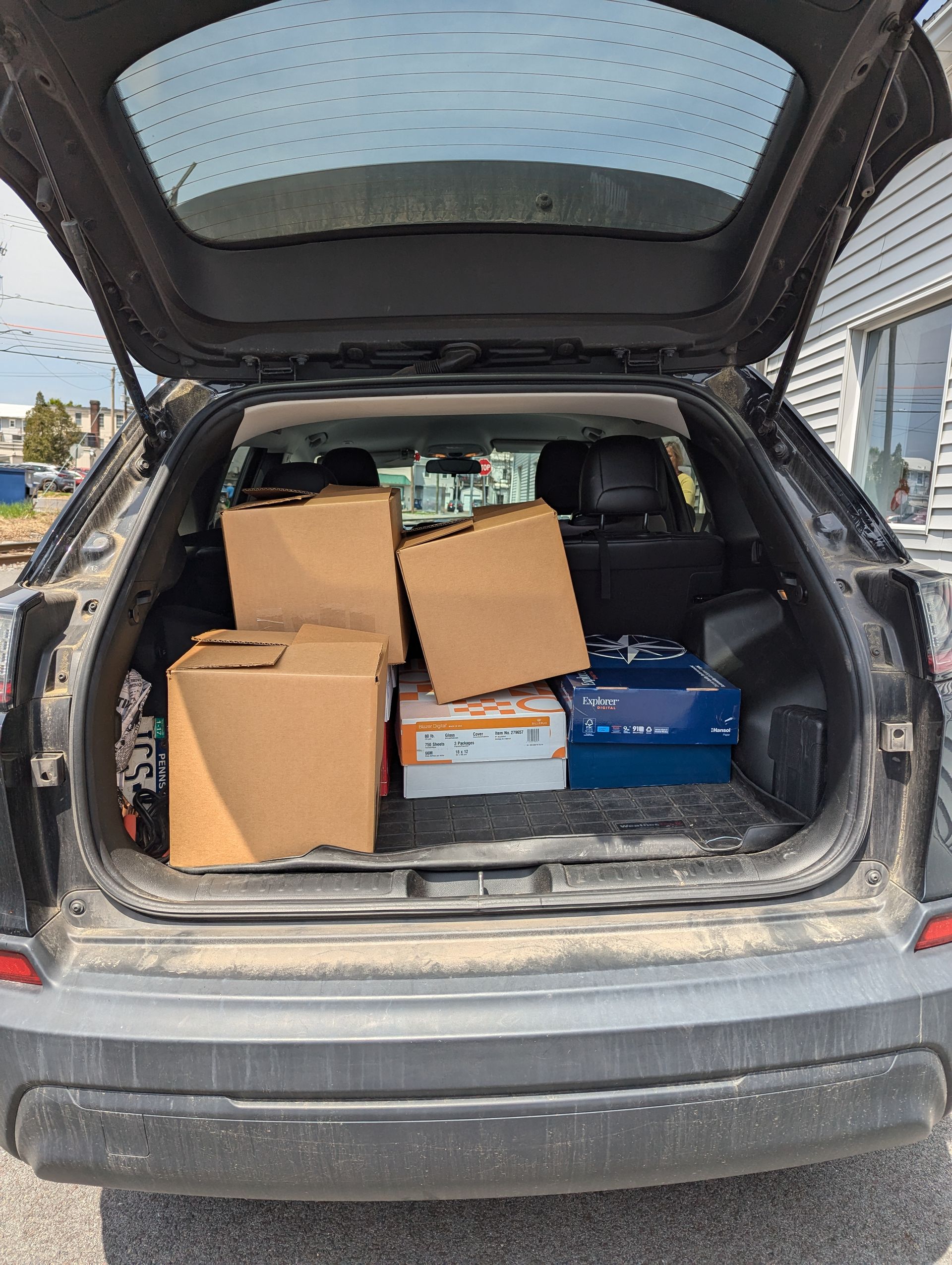Open SUV trunk filled with cardboard boxes, likely for moving or transporting goods.