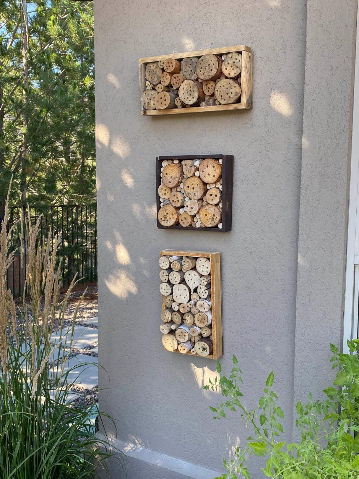 Three wooden boxes filled with logs are hanging on a wall.