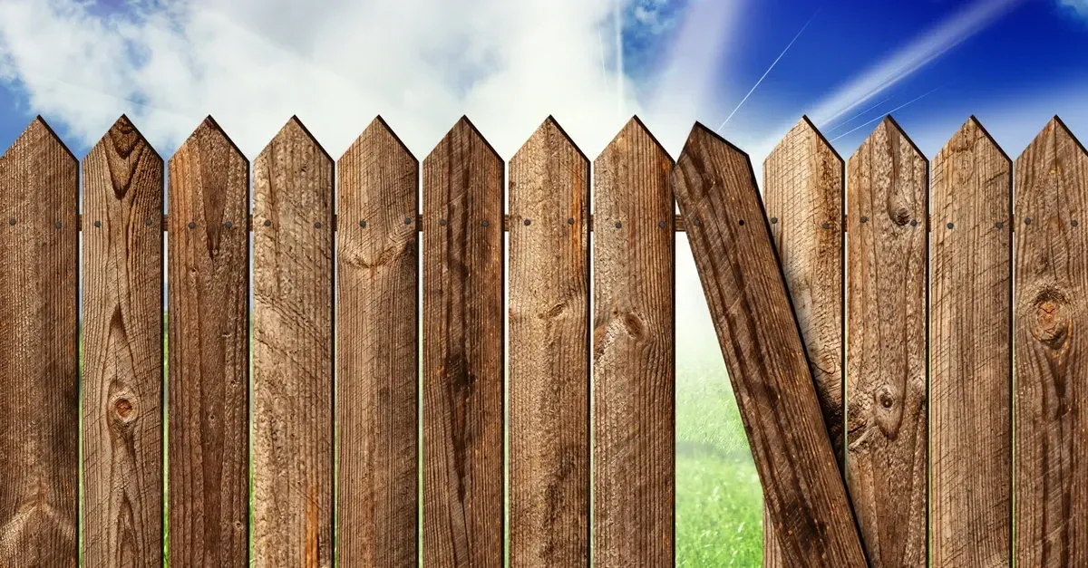A white house with a red door and a white picket fence in front of it.