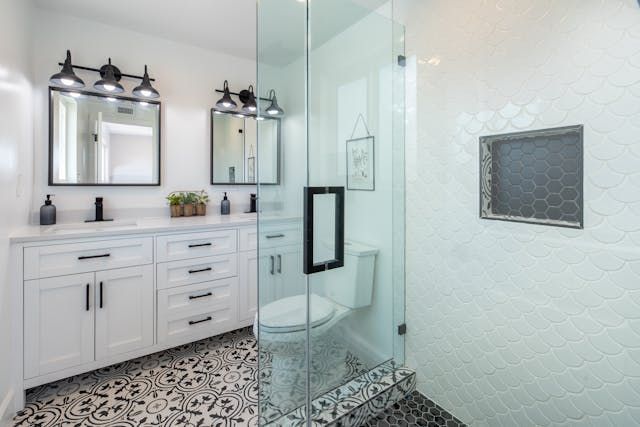 A bathroom with two sinks , a toilet , and a walk in shower.