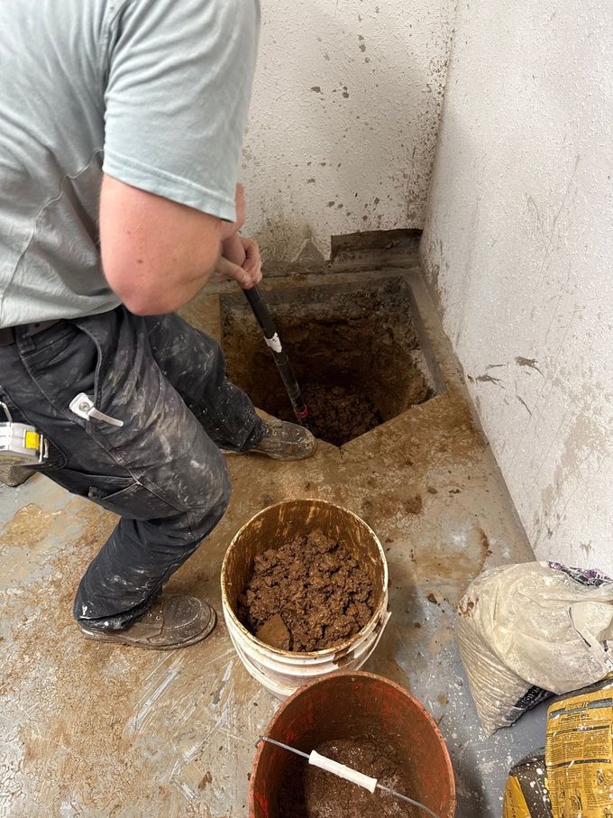 Hand rinsing a white sink drain with a flexible metal hose
