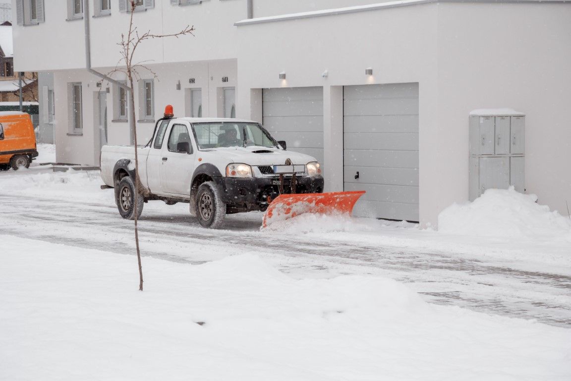 Pickup truck plowing snow in front of a white building