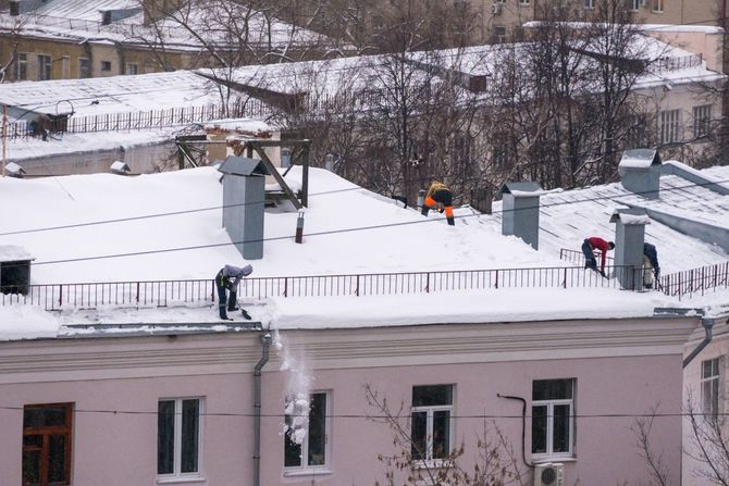 Snow-covered rooftop with workers near vents in a winter city scene