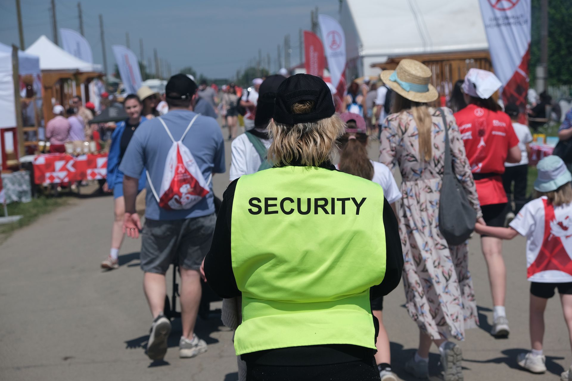 Security guard in neon yellow vest walking through a crowded outdoor event