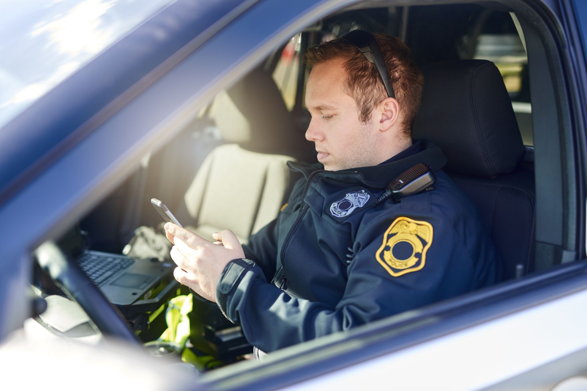 Police officer using a smartphone inside a patrol car