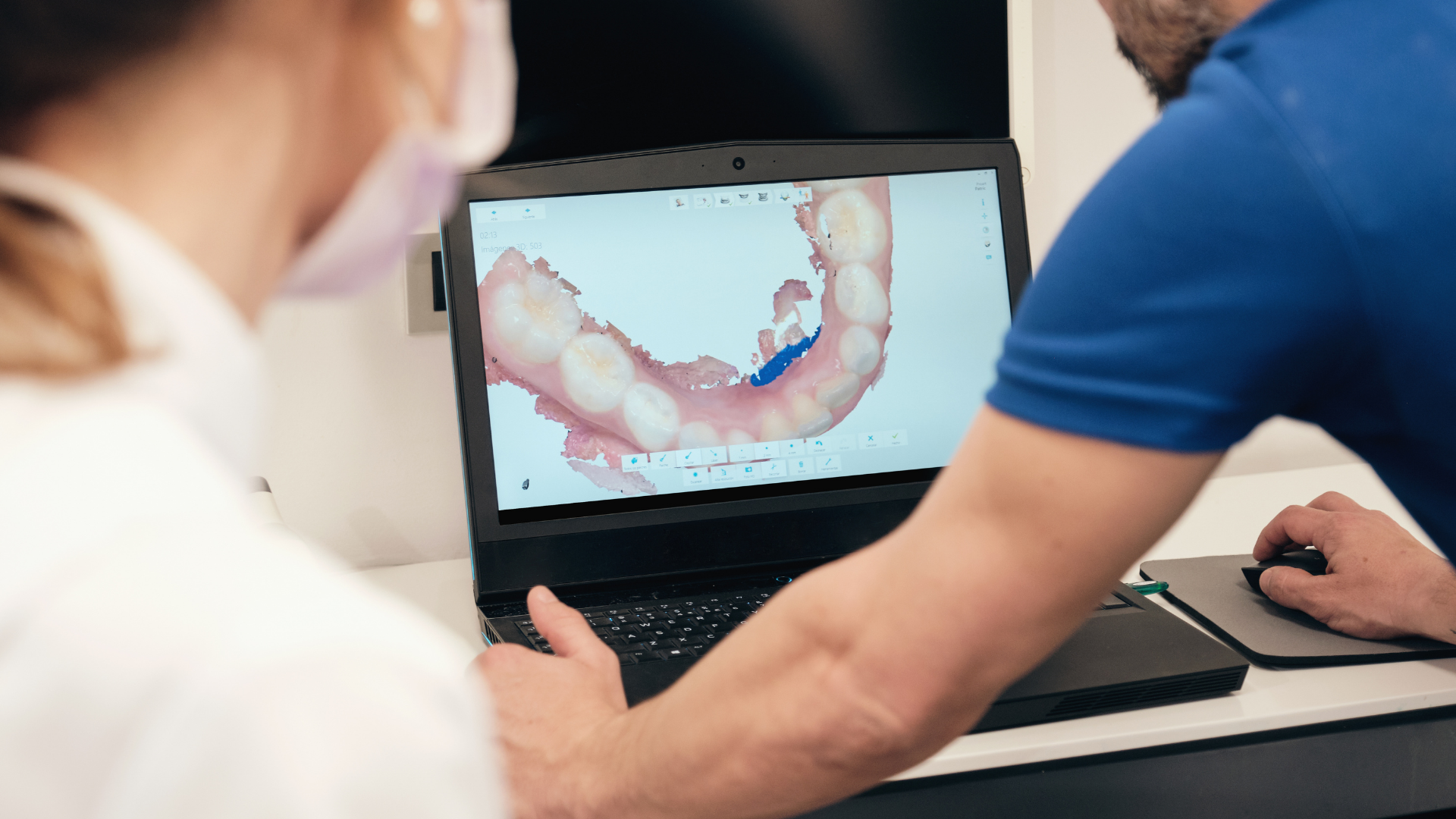 Two people reviewing a dental scan on a laptop at a desk