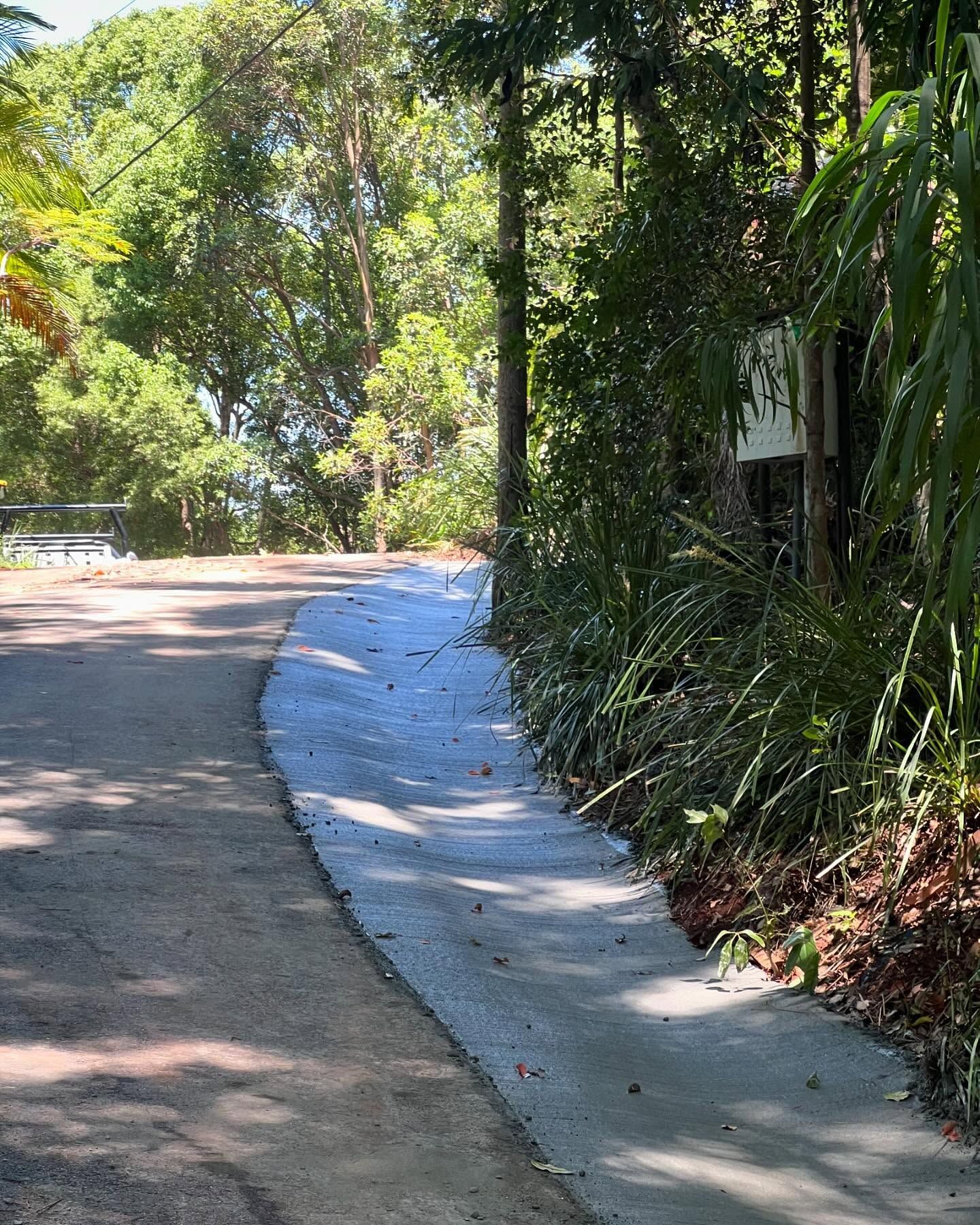 A paved pathway curving alongside a road, bordered by greenery and trees — All Concrete Creations in Robina, QLD