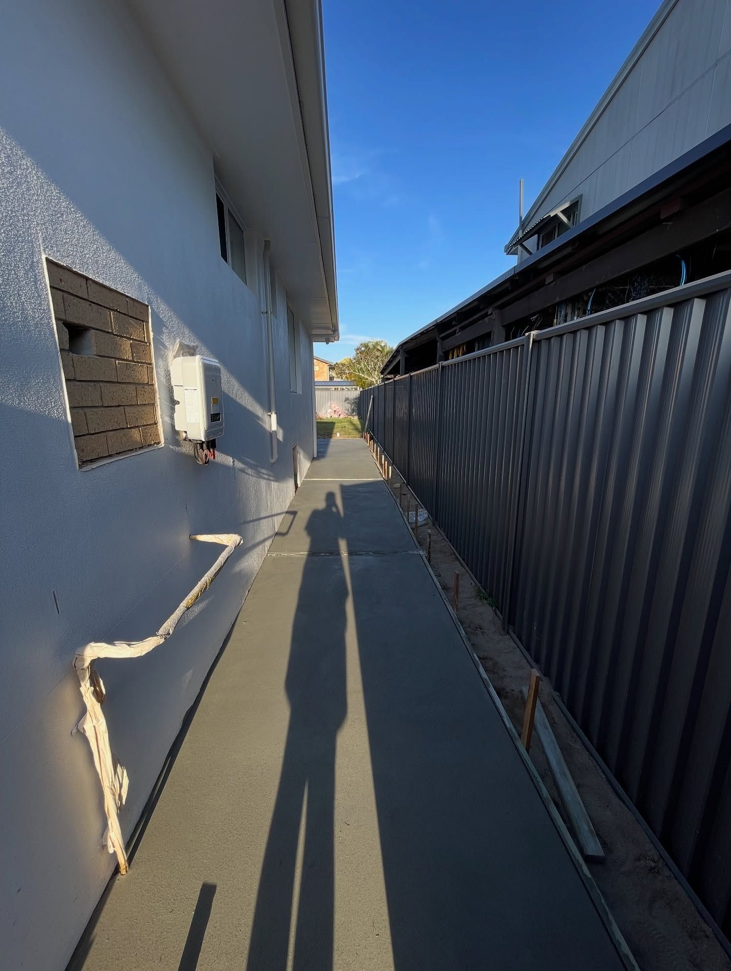Narrow Concrete Path Between a White Building and a Corrugated Metal Fence — All Concrete Creations in Kingscliff, NSW