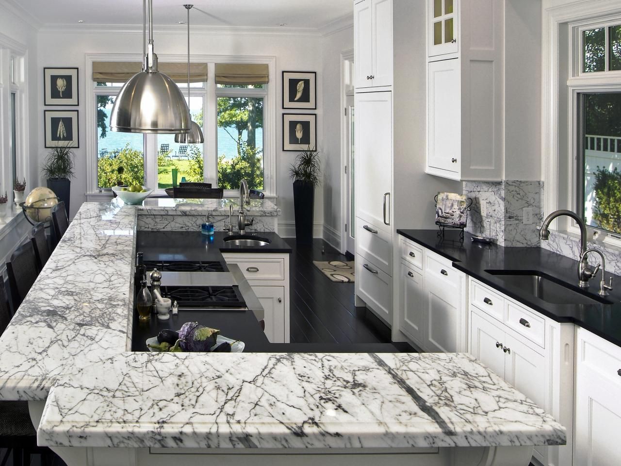 Elegant white kitchen with marble countertops, dark floor, and large windows.