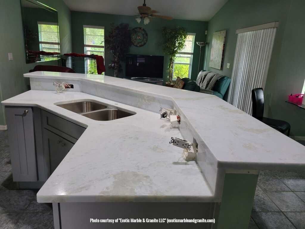 Kitchen island with white countertops, gray cabinets, and a sink.
