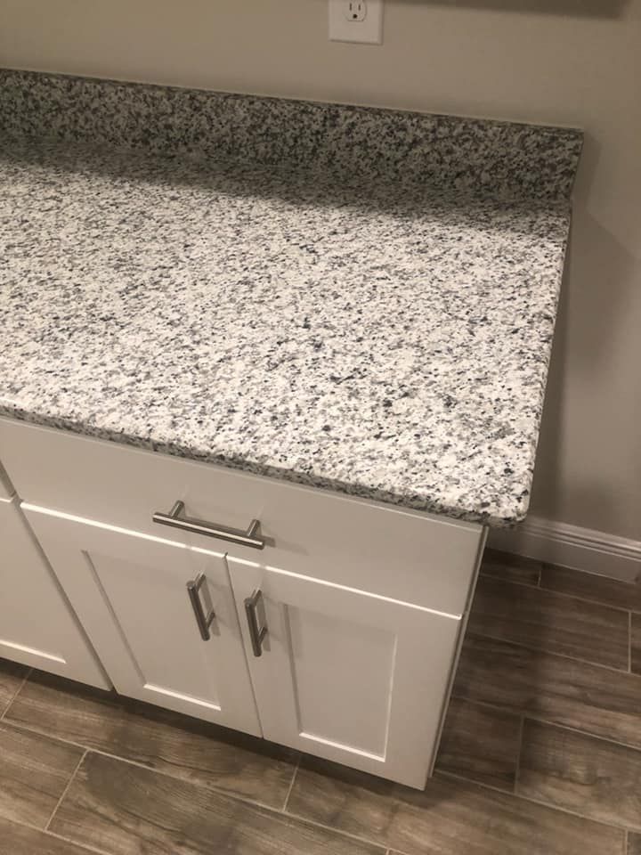 White cabinets with a speckled gray countertop and silver handles.