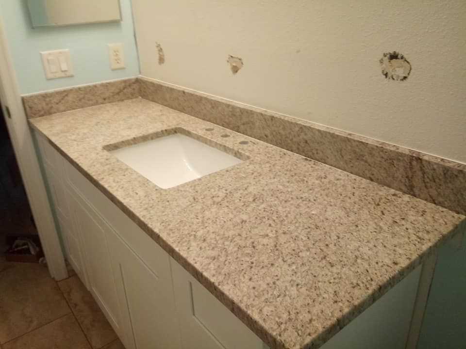 Bathroom vanity with light-colored granite countertop and white sink, against a light blue wall.