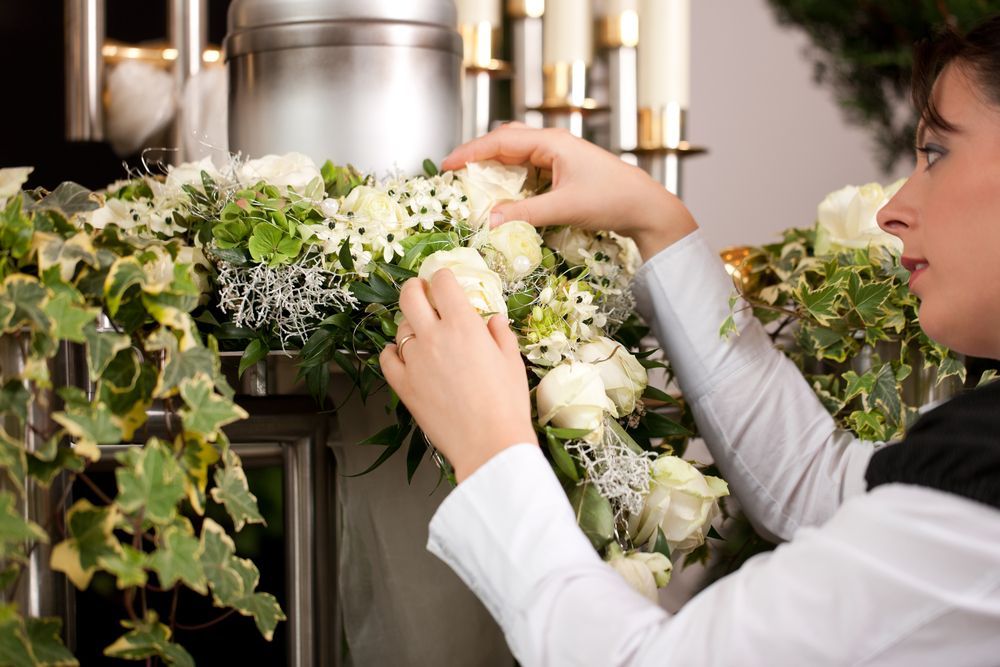 Woman Arranging White Flowers in a Floral Display — Finlayson & McKenzie Funeral Directors in Rockhampton City, QLD
