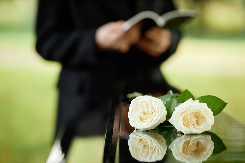 White Roses on Reflective Surface — Finlayson & McKenzie Funeral Directors in Emu Park, QLD