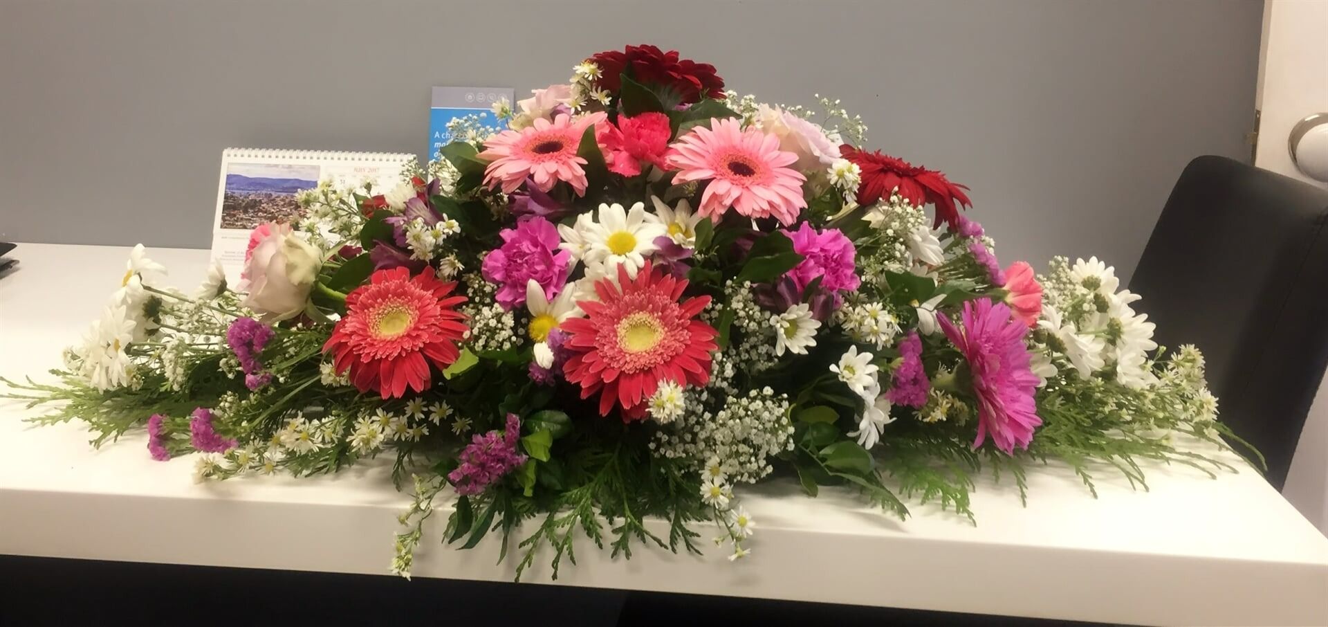 A Colourful Floral Arrangement on a White Table — Finlayson & McKenzie Funeral Directors in Rockhampton City, QLD